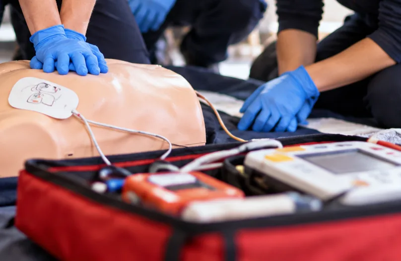 Defibrillator and first-aid kit beside a training mannequin